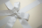 Preview: Die Brautkleidbox Stripes White & Gold wird mit einem weißen Satinband gebunden.