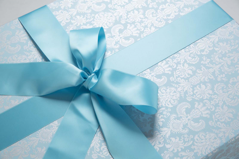 Die Brautkleidbox Tapestry Aqua wird mit einem aqua-farbenen Satinband gebunden.